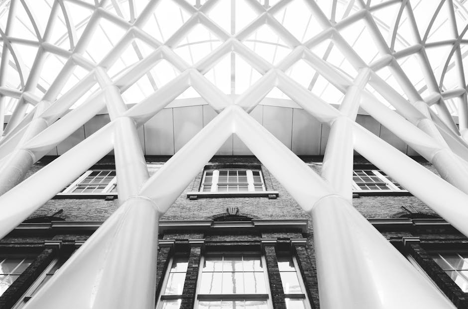 Inside Kings Cross station, the spacious platform features a high, curved glass and metal arched ceiling allowing natural light to illuminate the area. The platform surface is smooth paving, appearing